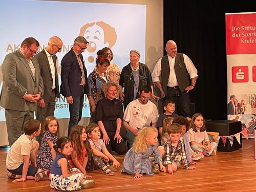 v.l. Hr. Schramm, Sparkassenstiftung; Oberbürgermeister Meyer; Hr. Rausch, Bürgerstiftung; Fr. Doumbaki, Heilpädagogin; Fr. Bambeck, Kita-Leitung; Fr. Schremmer u. Hr. Jansen, AKKU; davor Künstlerin Julia Timmer; Hr. Seeger, Moderation; die preistragenden Kinder; Foto: Bettina Kürschner